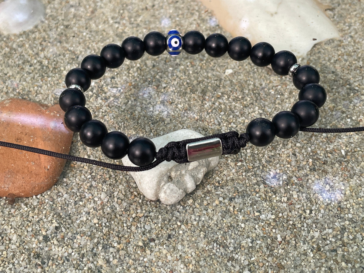 Black beaded bracelet with a metal clasp on a sandy surface