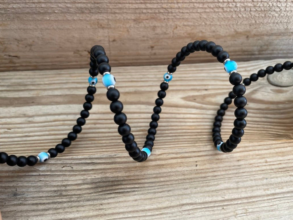 Two black beaded necklaces with blue accents on a wooden surface