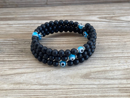 Black beaded bracelet with blue evil eye beads on a wooden surface