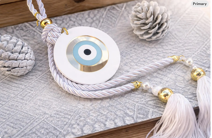 Decorative evil eye pendant with tassels on a textured surface