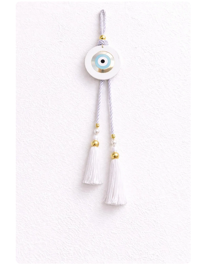 Decorative evil eye charm with tassels on a white background