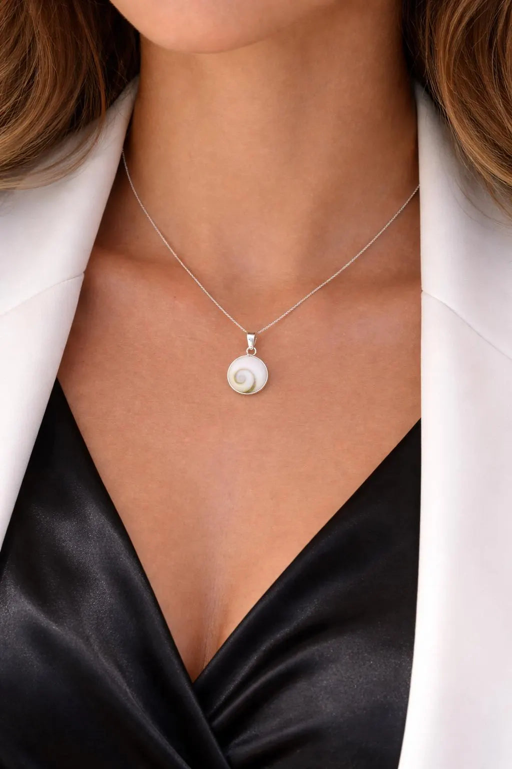 Necklace with a pendant worn by a person in a white shirt and black top.