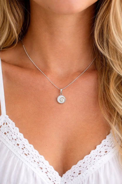 Silver necklace with a pendant worn by a person in a white top