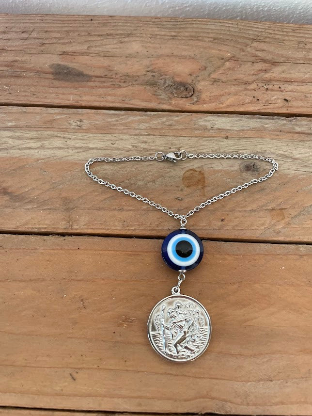 Necklace with a pendant and evil eye charm on a wooden surface