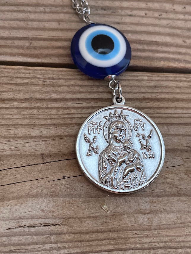 Necklace with a silver pendant and blue evil eye charm on a wooden surface