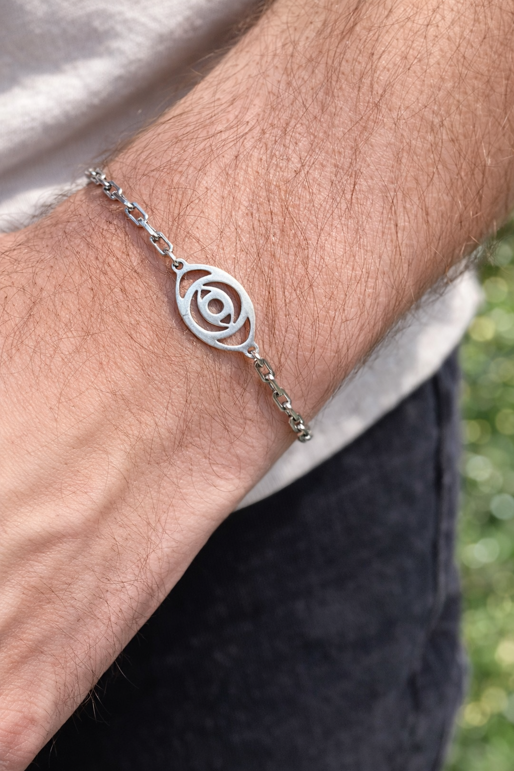 Silver bracelet with a circular design on a wrist against a blurred natural background