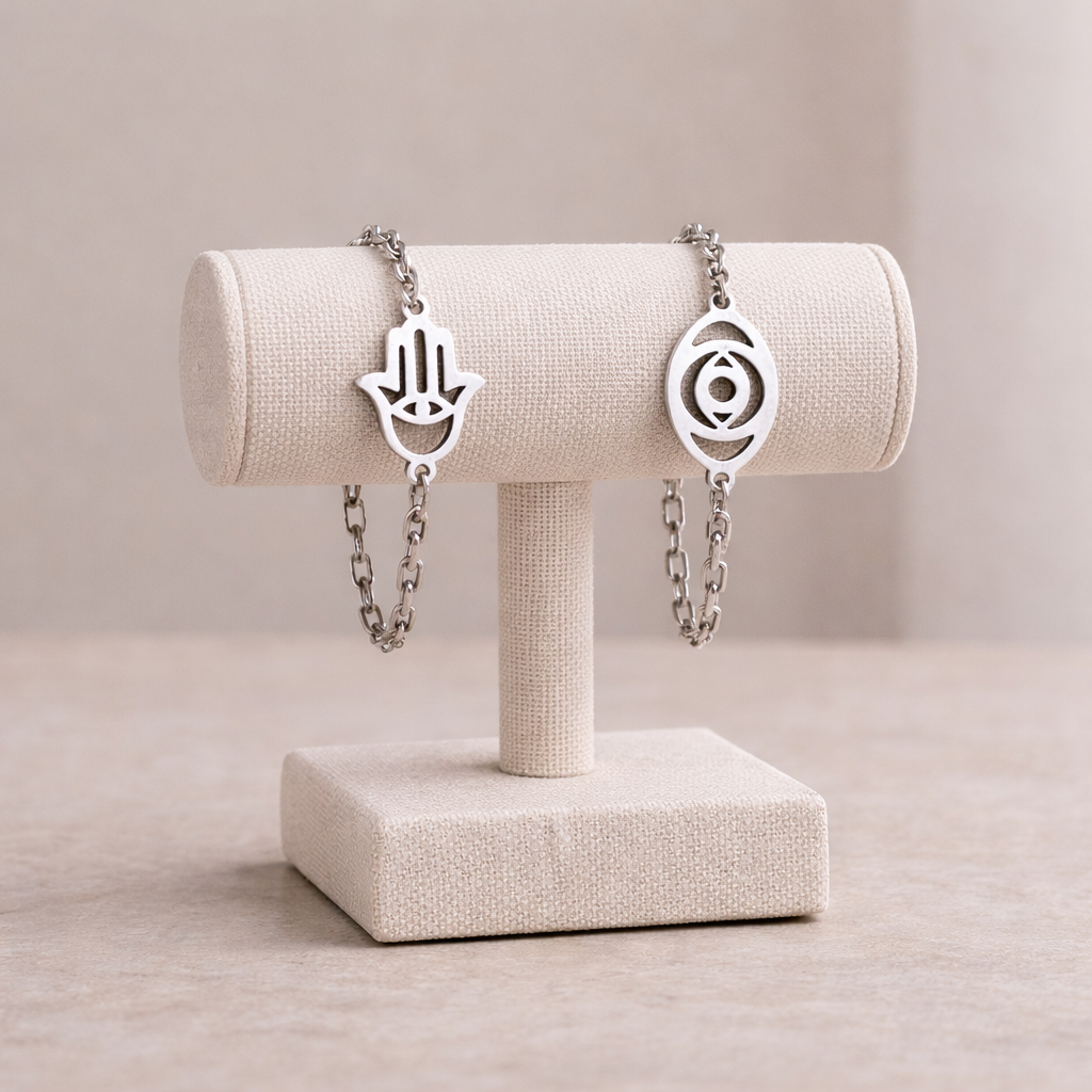 Two silver bracelets on a beige jewelry stand against a neutral background