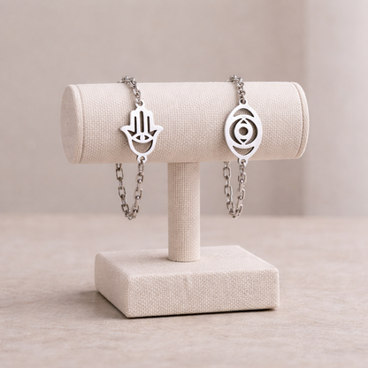 Two silver bracelets on a beige jewelry stand against a neutral background