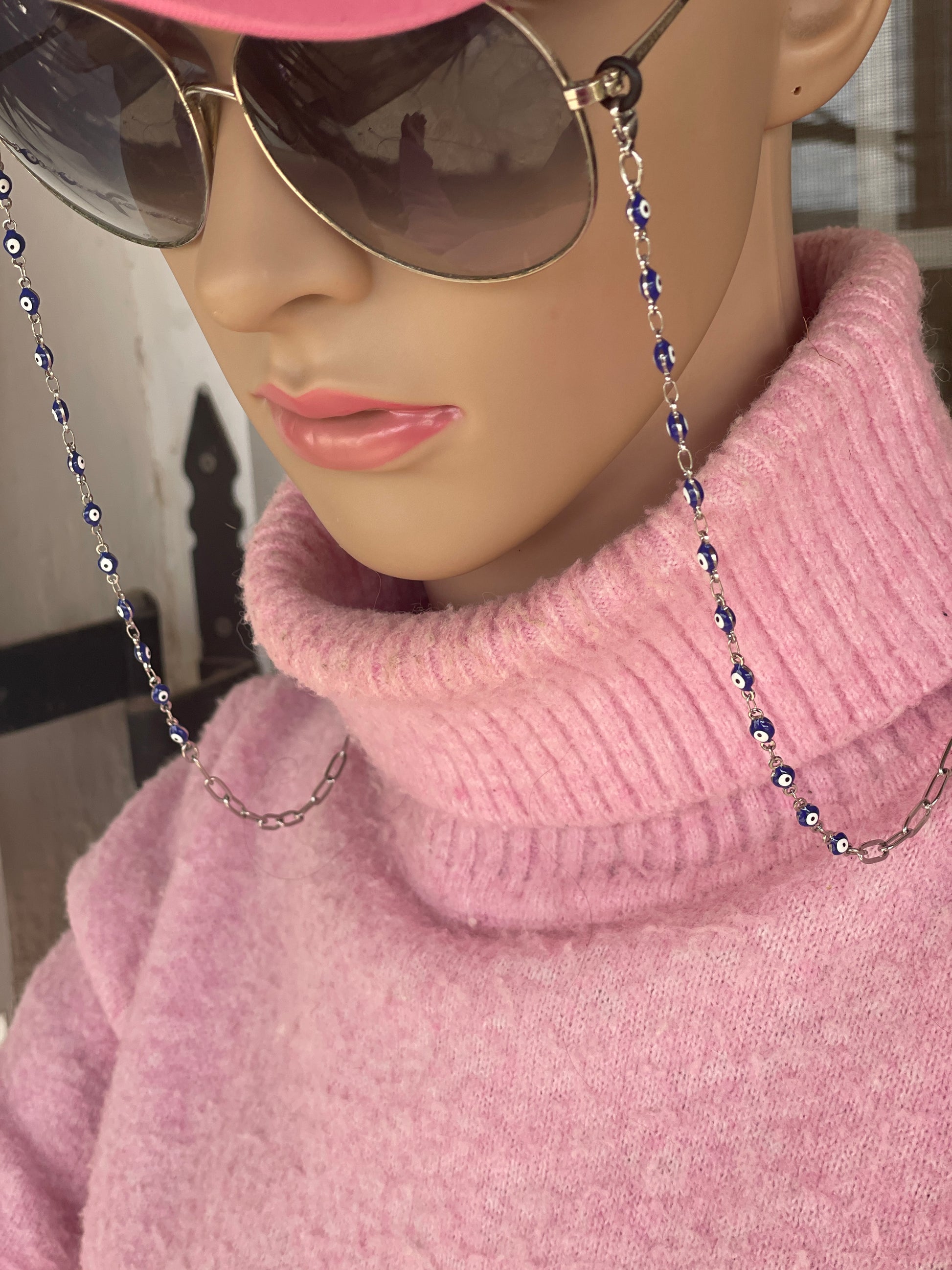 Mannequin head wearing a pink sweater with sunglasses on a chain