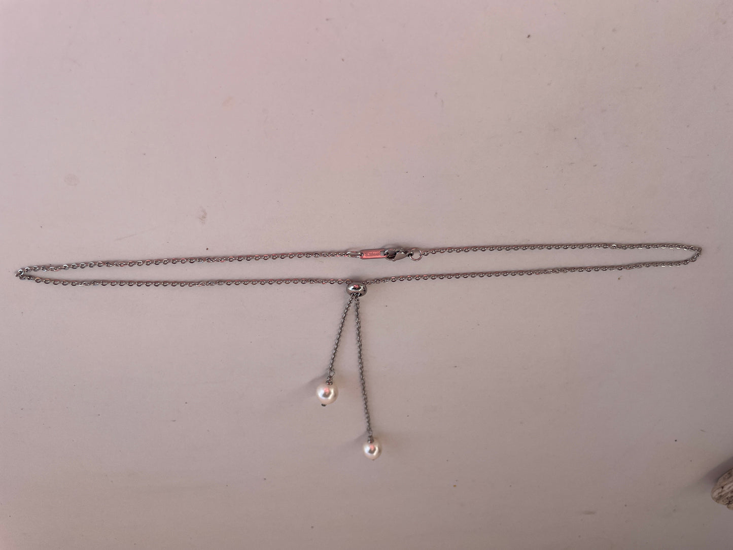 Necklace with two small pendants on a plain background