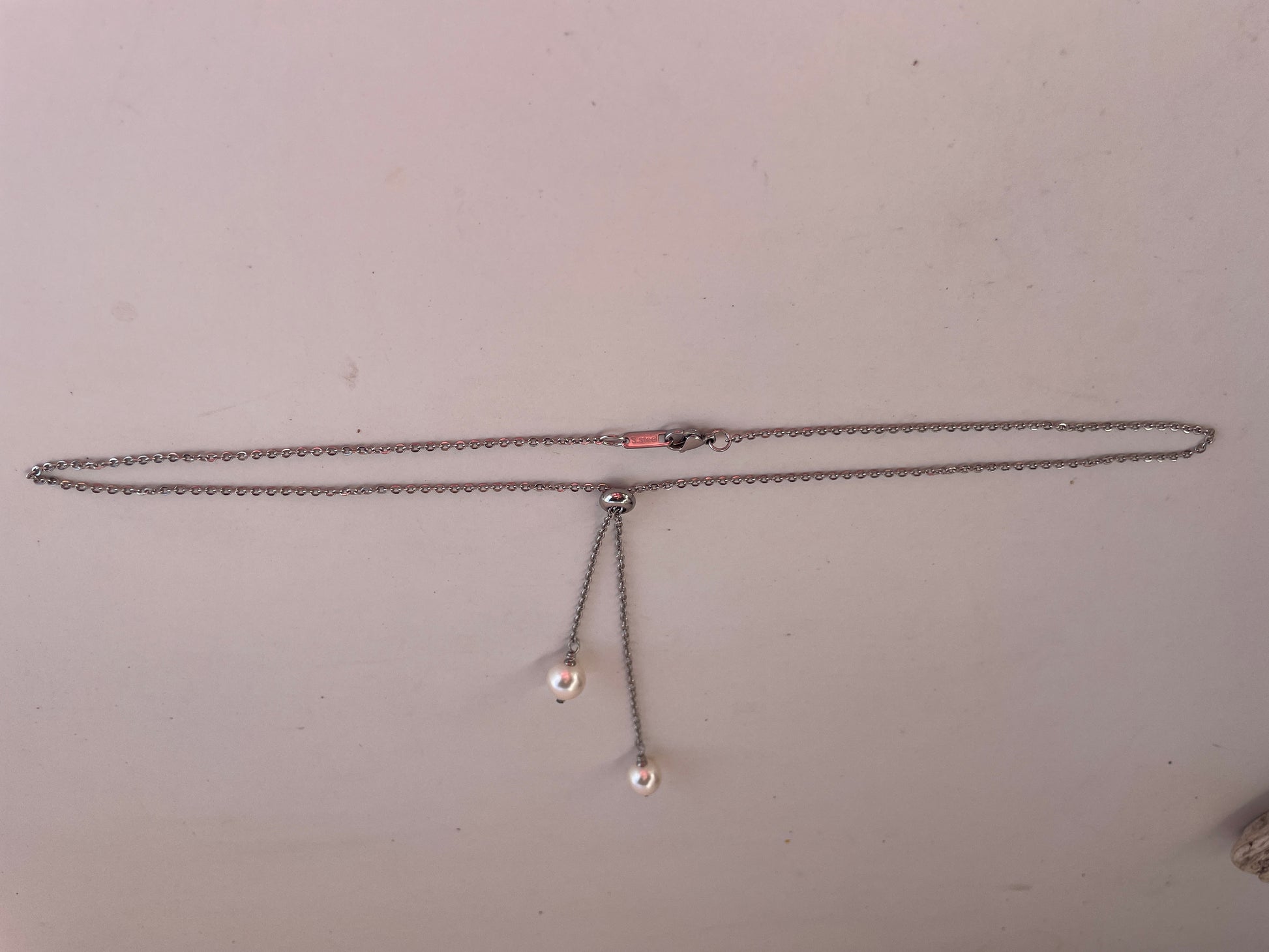 Necklace with two small pendants on a plain background