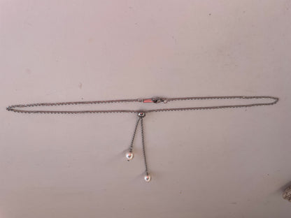 Necklace with two small pendants on a plain background