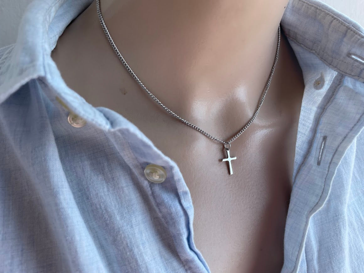 Mannequin wearing a light blue shirt with a necklace featuring a cross pendant.