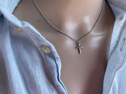 Mannequin wearing a silver necklace with a cross pendant