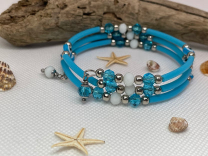 Blue beaded bracelet with silver accents on a textured surface with starfish and shells.