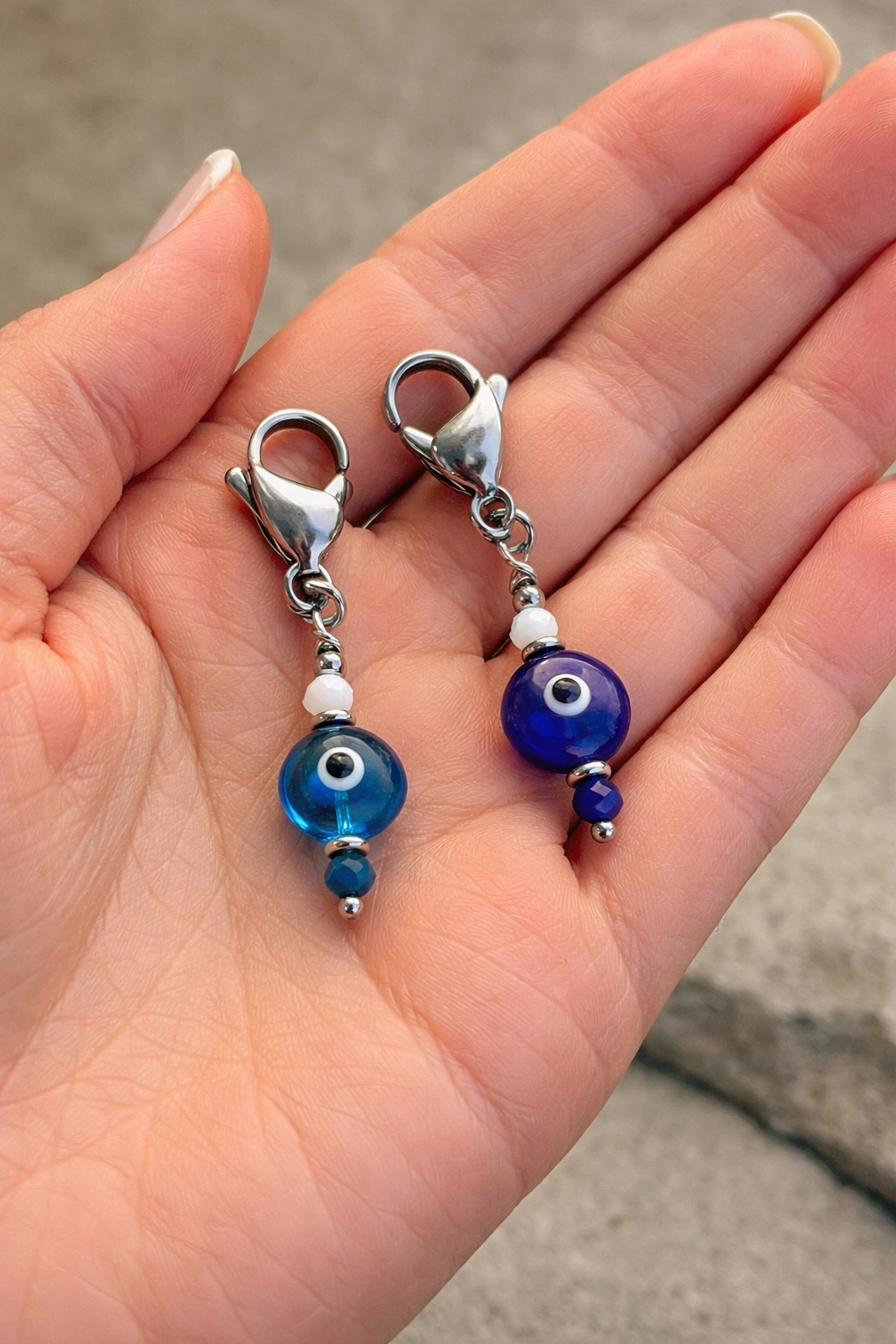 Blue beaded earrings with silver clasps held in a hand against a neutral background