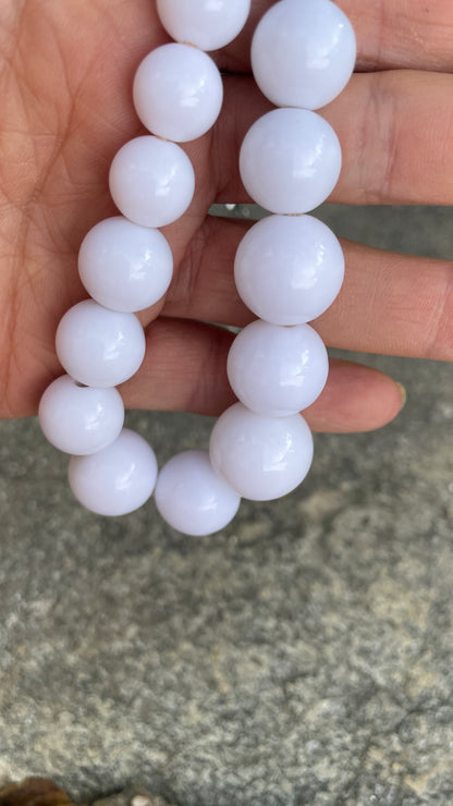 White beaded bracelet held by a hand against a blurred background