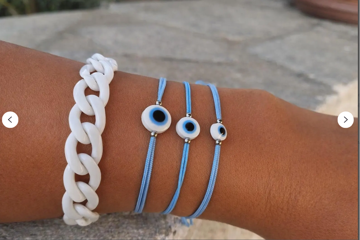 Close-up of a wrist wearing a white chain bracelet and three blue bracelets with eye designs.