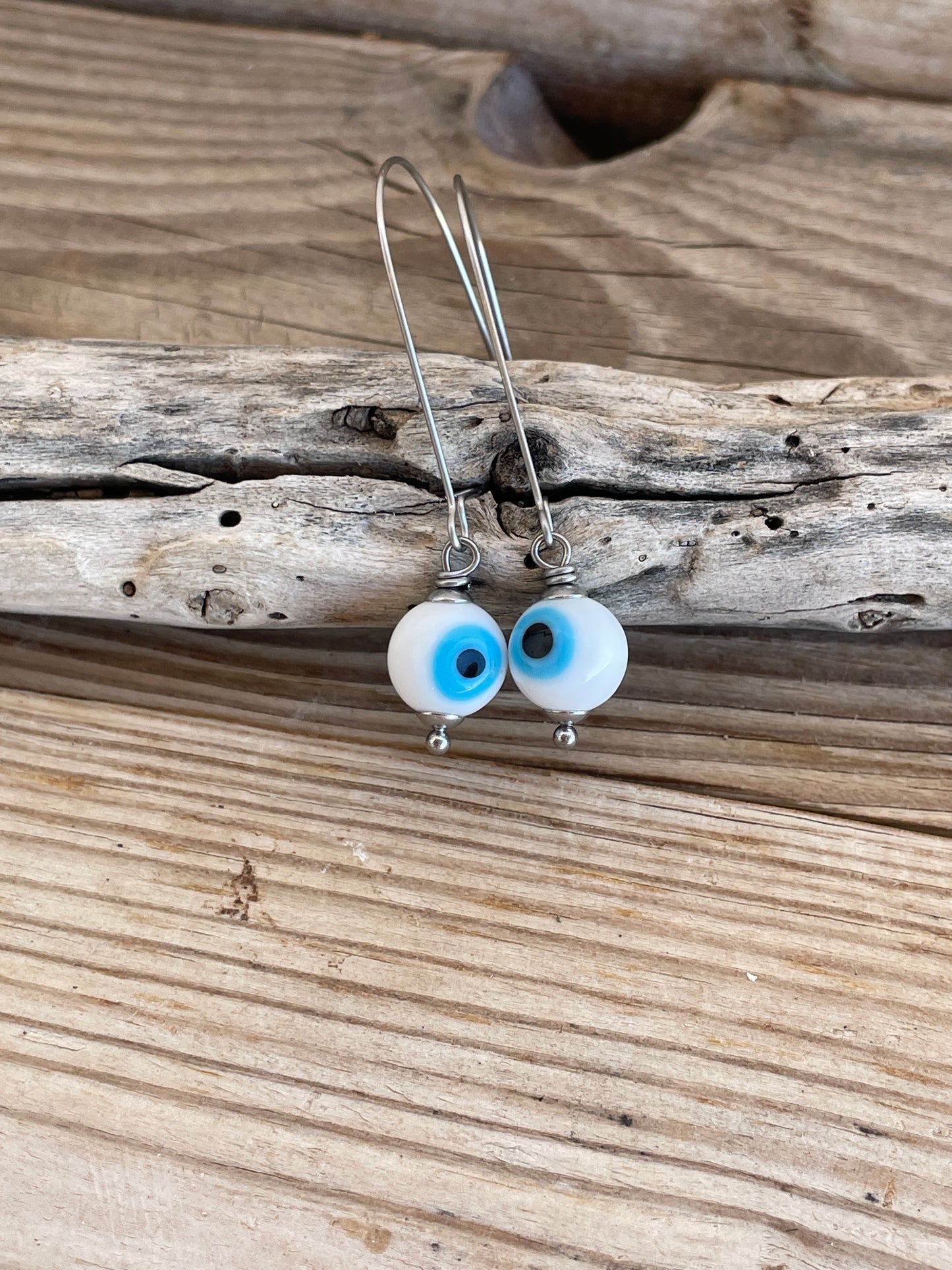 Pair of earrings with blue and white beads on a wooden surface