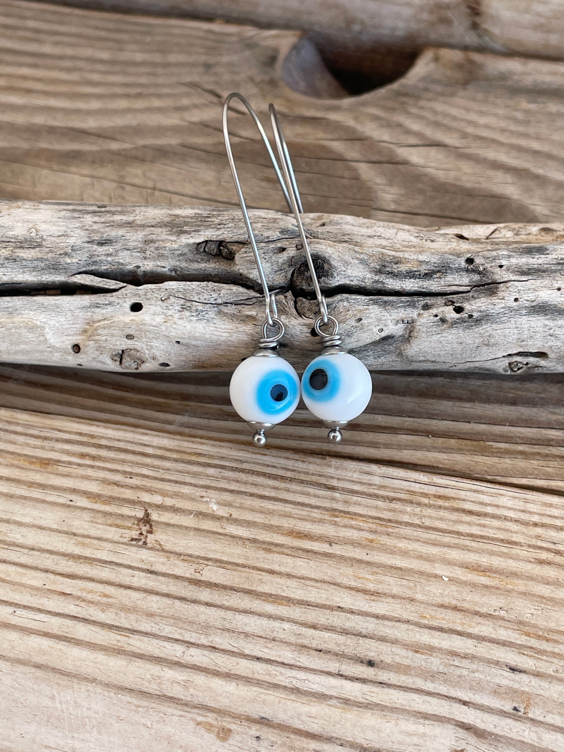 Pair of earrings with blue and white beads on a wooden surface