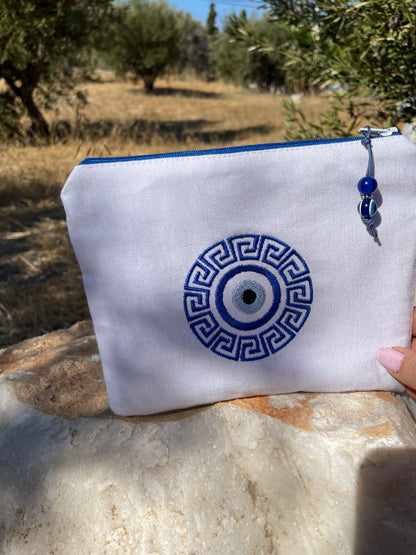 White pouch with blue decorative pattern held outdoors on a stone surface