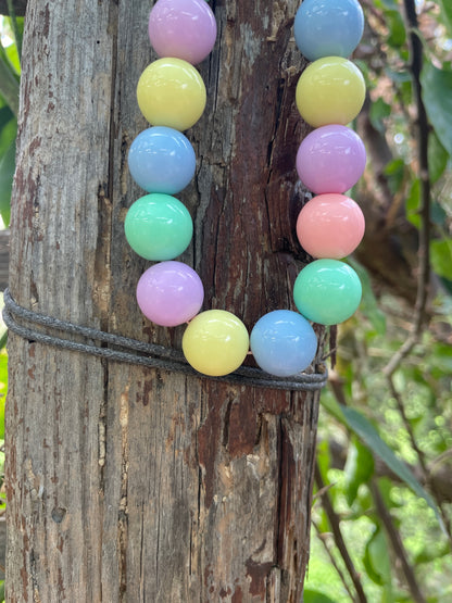 Colorful beaded bracelet on a wooden log with greenery in the background