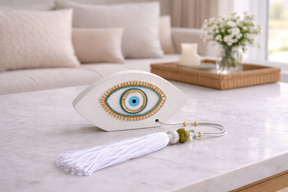 Decorative eye-shaped object with tassel on a surface, possibly a table or shelf.
