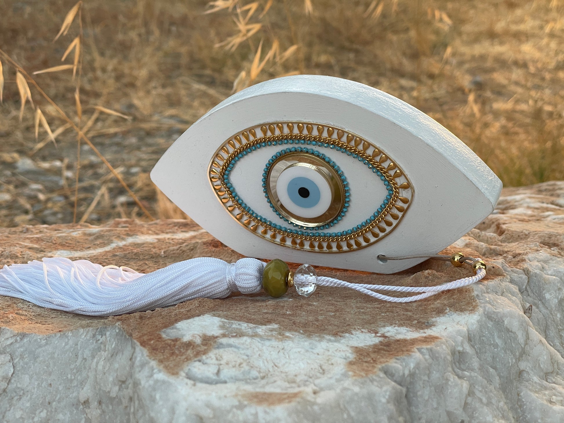 Decorative eye-shaped object with tassel on a stone surface