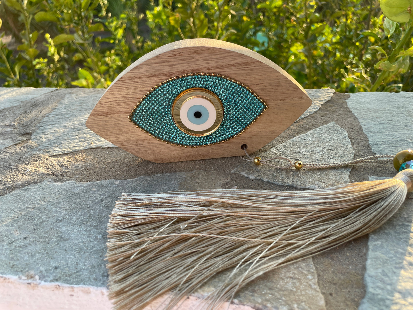 Decorative eye-shaped object with tassel on a stone surface