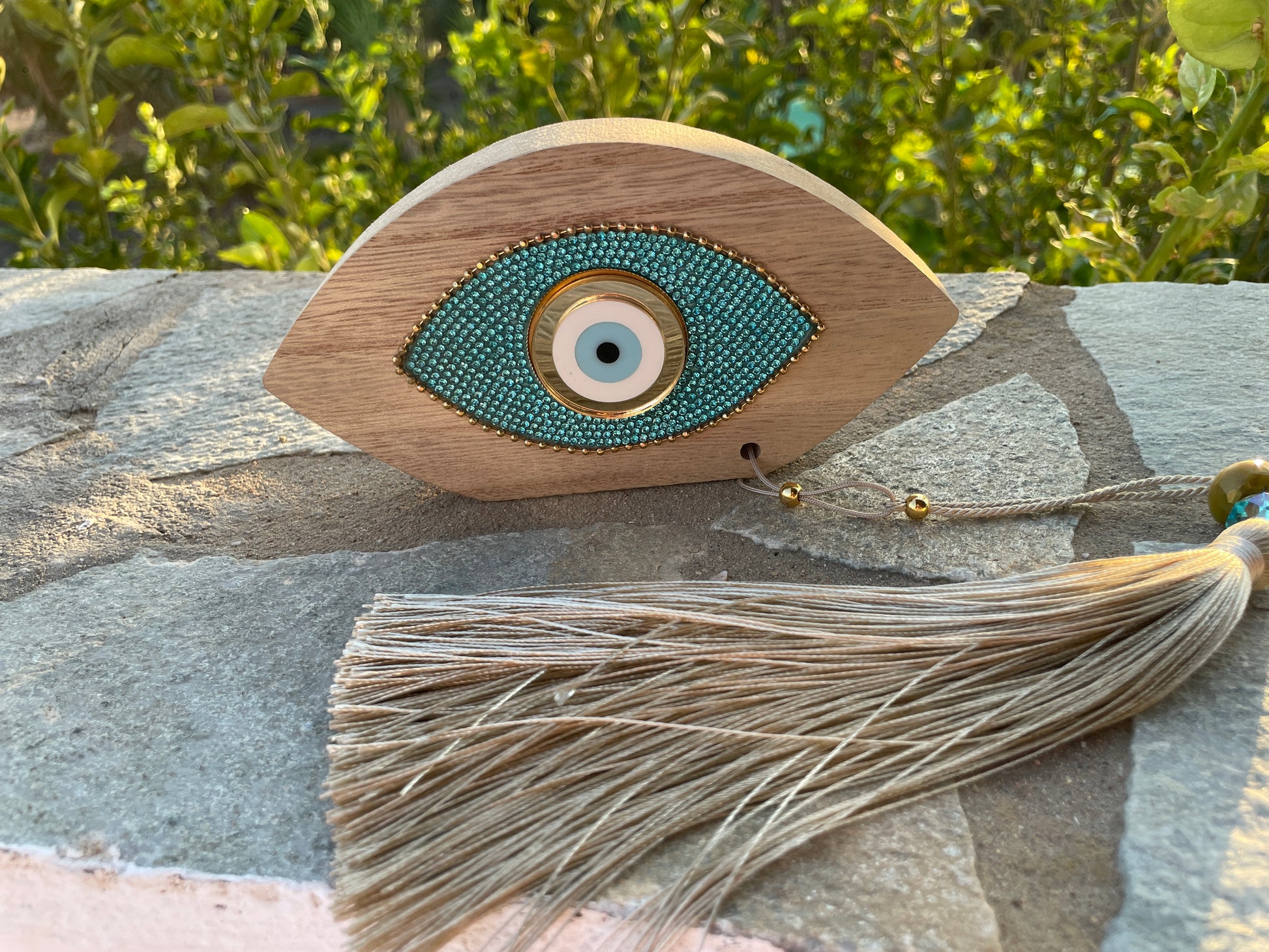 Decorative eye-shaped object with tassel on a stone surface