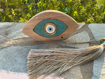 Decorative eye-shaped object with tassel on a stone surface