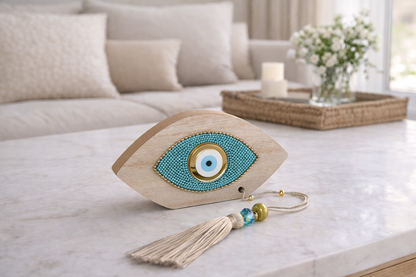 Decorative eye-shaped object with tassel on a marble surface in a living room setting.