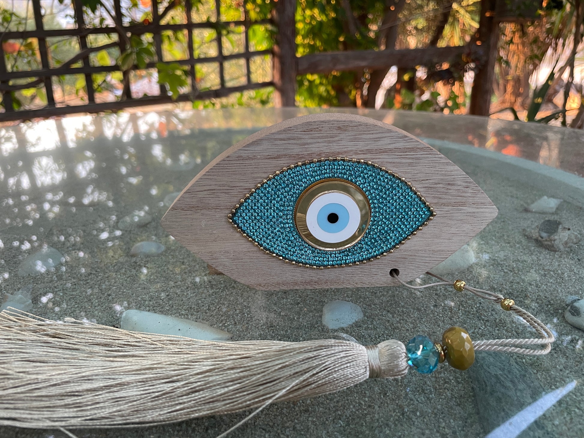 Decorative eye ornament with tassel on a reflective surface