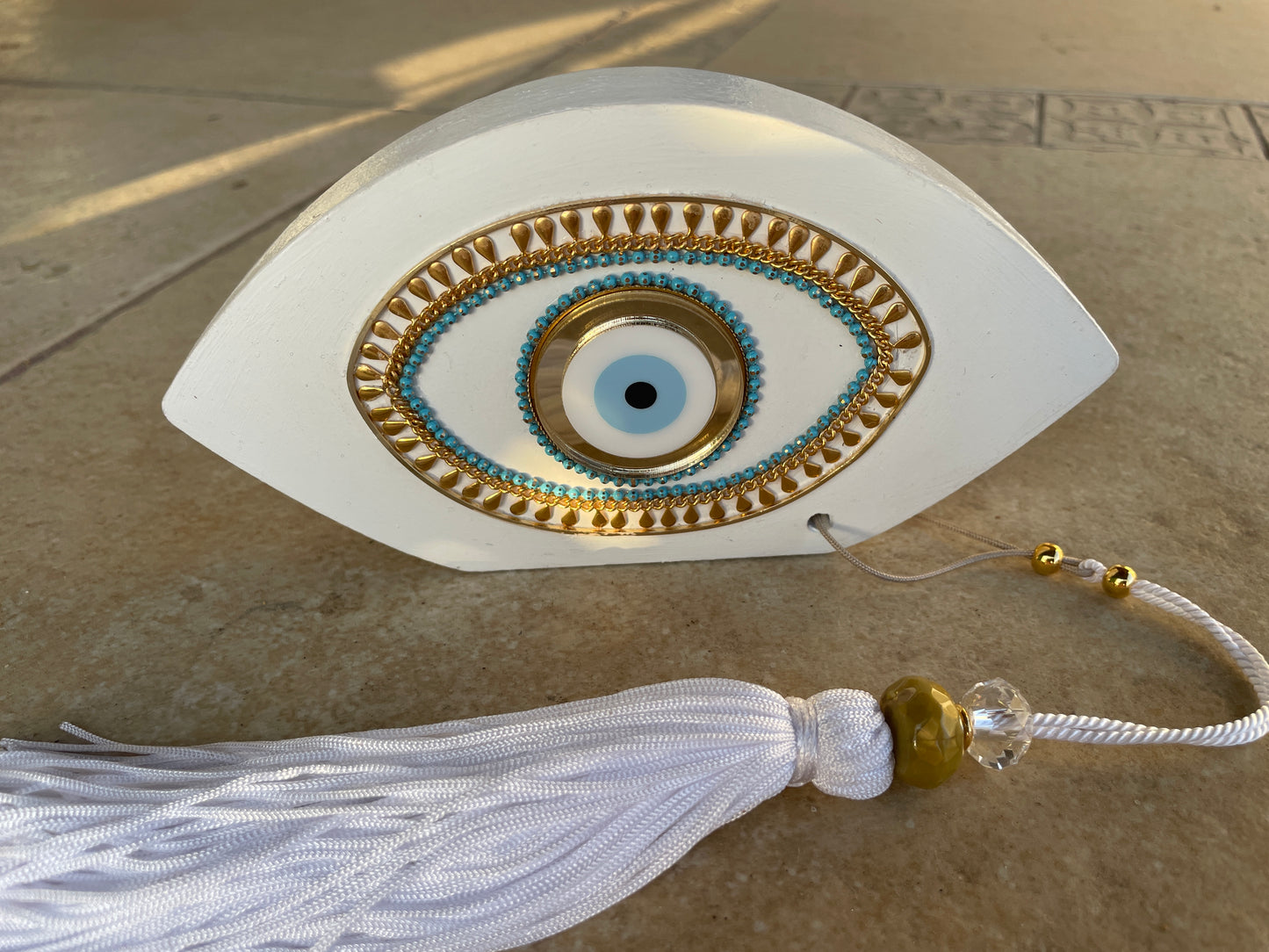 Decorative eye-shaped object with tassel on a textured surface