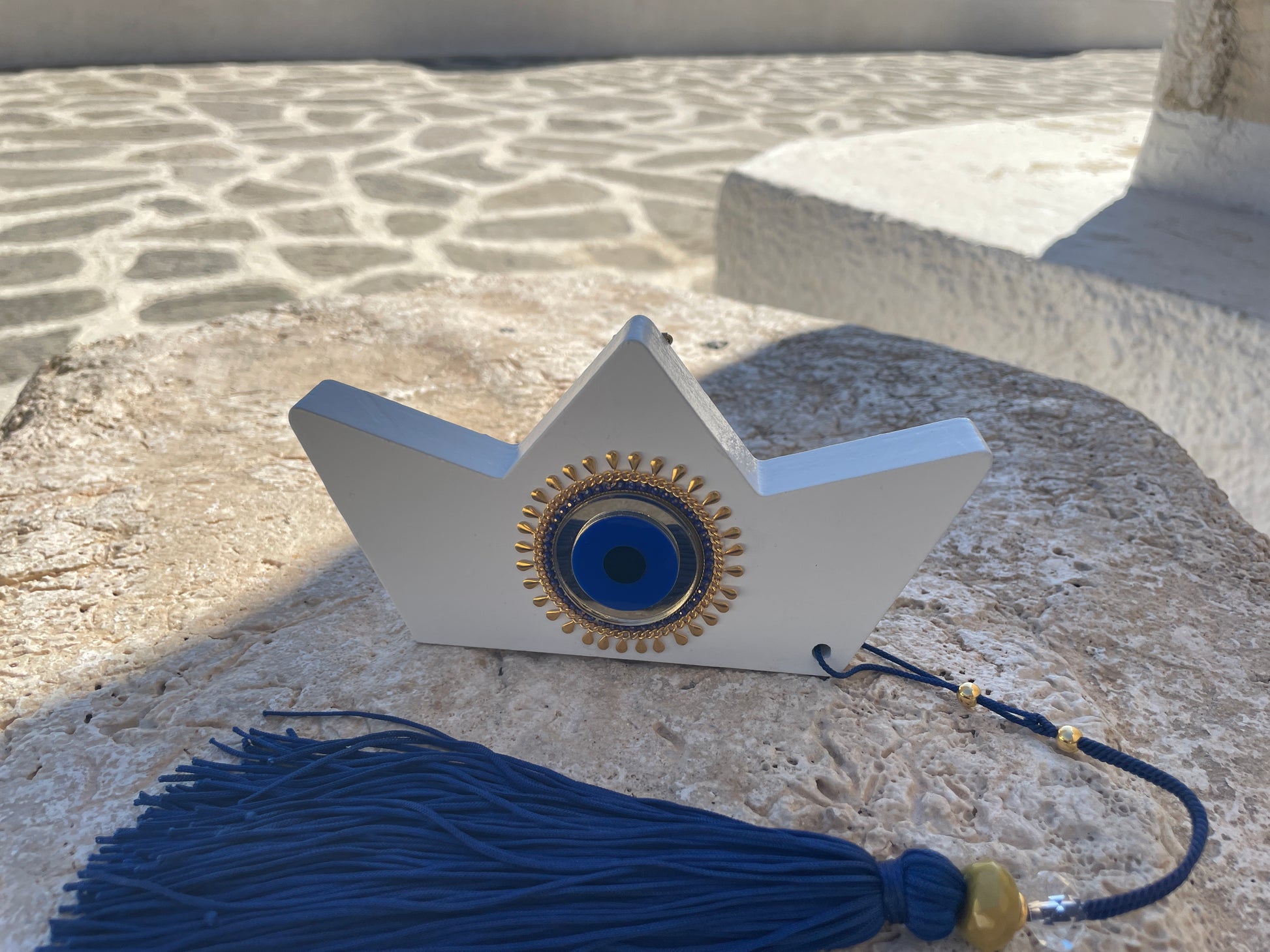 Decorative boat with blue eye design and tassel on a stone surface