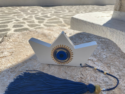 Decorative boat with blue eye design and tassel on a stone surface