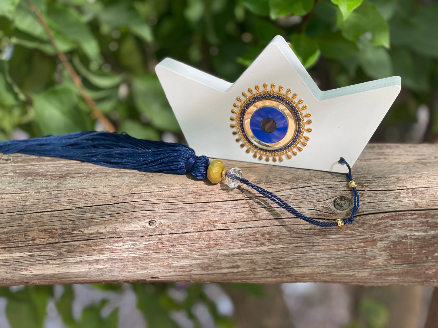 Decorative boat with blue evil eye and with blue tassel on a wooden surface
