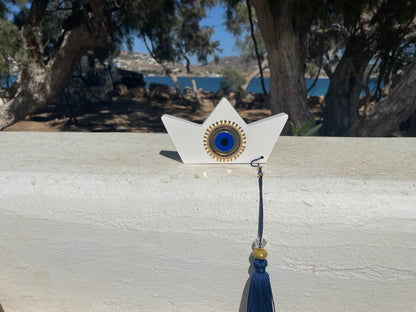 Decorative star-shaped object with a blue center and tassel on a wooden surface.