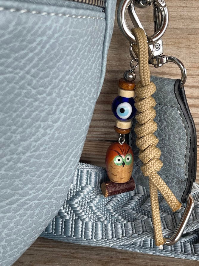 Keychain with owl charm and braided rope on a textured surface