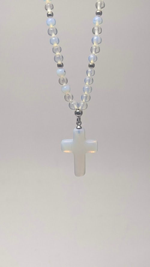 Moonstone cross charm pendant hangs from a strand of round moonstone beads, featuring a stainless steel clasp.