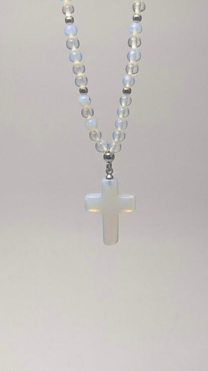Moonstone cross charm pendant hangs from a strand of round moonstone beads, featuring a stainless steel clasp.